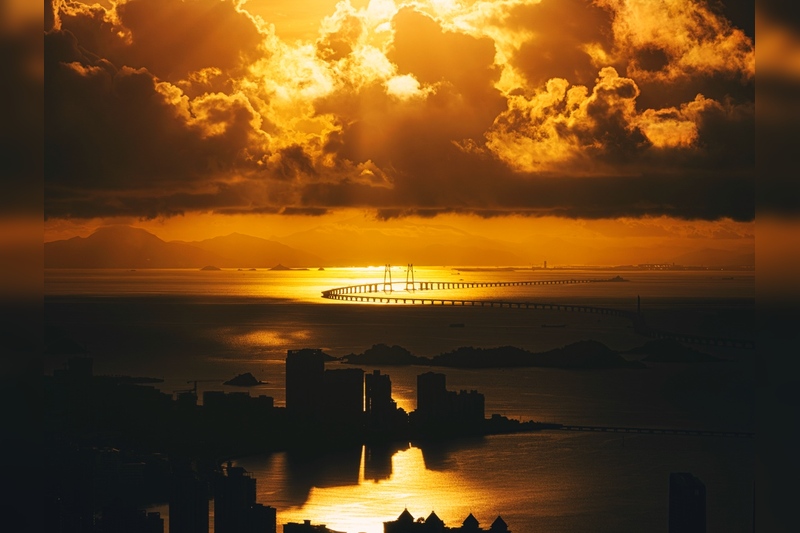 《金光港珠澳》2023年7月25日，广东省珠海市。世纪工程港珠澳大桥在日出的金光中盘踞在珠江入海口。