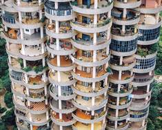 《人造密度》“密度”一词，本是人口统计学的专属术语，而后伴随人口的持续致密、住宅的日益紧凑与人类活动范围的不断扩张，如今已演变为具有社会学意义的独特景观，它与超真实、消费主义、视觉噪音等概念紧密相连。我的镜头始终聚焦于社会空间里密集的人造景观，通过多重曝光、长焦镜头拍摄等手法，刻意放大这份密集感带来的视觉张力。依托无人机摄影技术进步所带来的高像素成像，再结合新地形学客观冷峻的摄影风格，最终让观者直观感受到“人造密度”的强烈视觉冲击。这些高密度景观，既是人类智慧的凝结，亦是欲望的投射。只是在追求效率、增长与消费的进程中，我们是否也在无形中为自己建造了一座华丽的囚笼？（组图拍摄于2019年至2025年间）#热爱依燃 1.参差交错的露台2.钢铁森林间的亭阁3.五层式立交枢纽4.大山上的光伏铠甲5.华灯初上的夜市6.赫鲁晓夫楼群像7.仓库的集装箱8.新能源汽车超级工厂9.堆放的共享单车